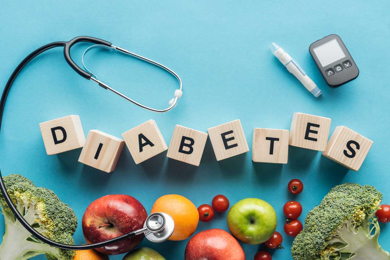 Diabetes lettering surrounded by items that help screen and manage diabetes, including glucose test, healthy fruits and vegetables and a doctors stethoscope as a symbol of professional medical treatment