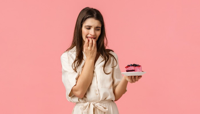 A woman thinking to substitute a cake with healthy snack as a tip to combat overindulgence during Christmas